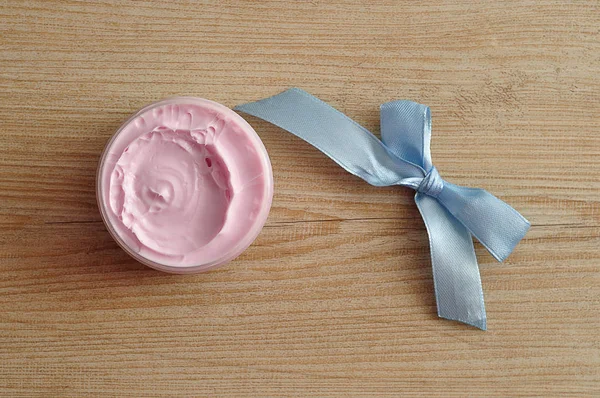 Un pot de lotion pour le corps rose avec un noeud bleu — Photo