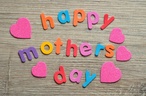 Щасливі матері день в барвистих листах на дерев'яному фоні з рожевими серцями — стокове фото
