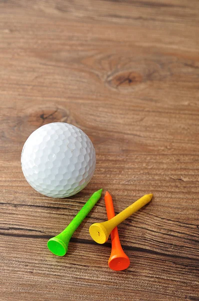 Uma bola de golfe com T 's isolado em um fundo de madeira — Fotografia de Stock