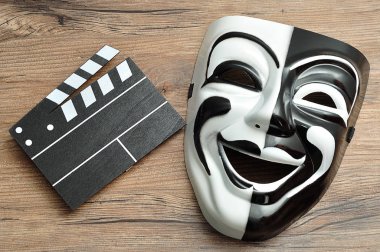 Siyah-beyaz film yönetim kurulu ve bir ahşap zemin üzerine bir tiyatro maskesi