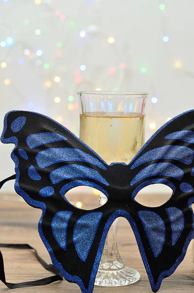 Синяя маска в форме бабочки с бокалом шампанского — стоковое фото