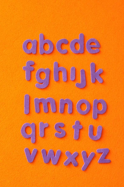 Алфавіт фіолетовими літерами на помаранчевому тлі — стокове фото