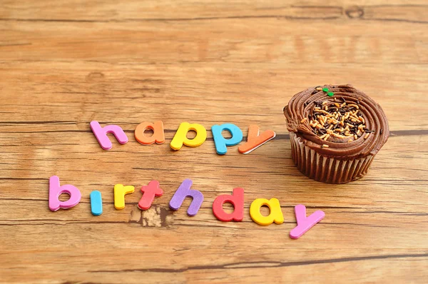Happy birthday in colorful letters with a chocolate cupcake