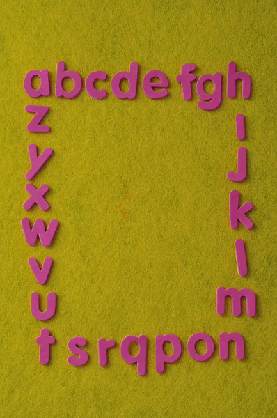 Алфавит розовыми буквами на желтом фоне — стоковое фото
