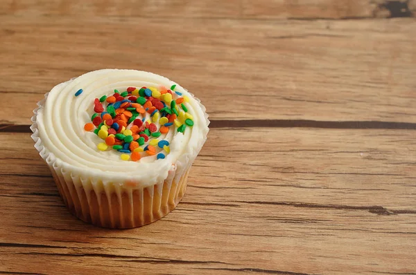 Um cupcake decorado com aspersores coloridos — Fotografia de Stock