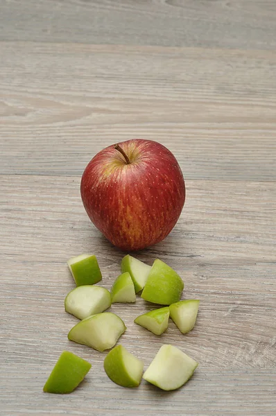 A red apple displayed with a cut up green apple