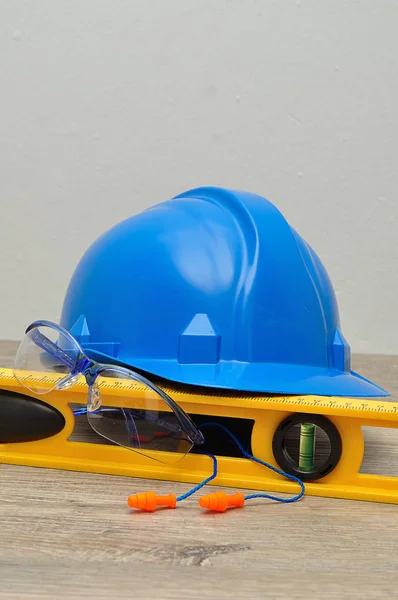 A hardhat, level, safety spectacles and earplugs