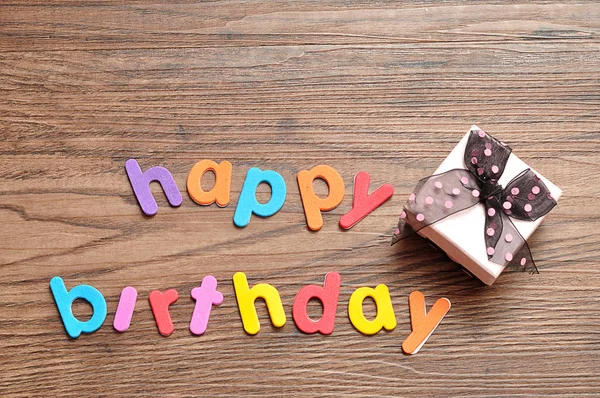 Happy birthday in colorful letters with a pink gift box