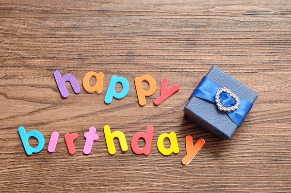 Happy birthday in colorful letters with a blue gift box