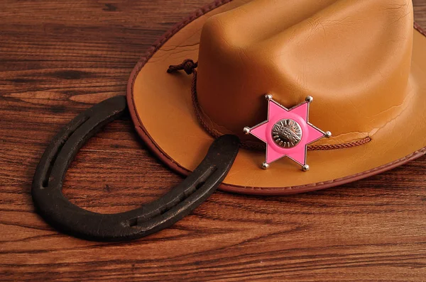 Una insignia del sheriff con un sombrero de vaquero marrón y una herradura de caballo — Foto de Stock