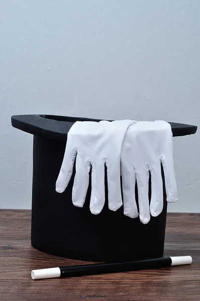 A magician hat with a pair of gloves and a wand