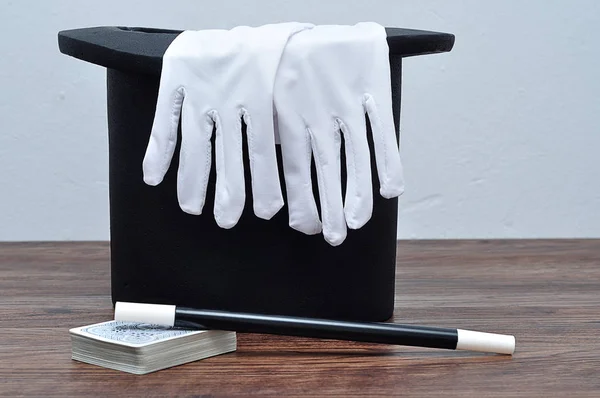 A magician hat with a pair of gloves, a wand and cards