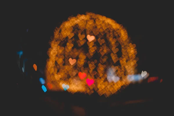 Hearts bokeh on street of evening city in dark texture — Stock Photo, Image