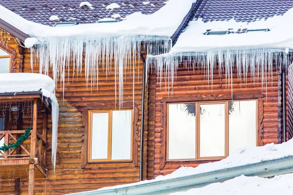 Long icicles hang over windows on roof in hotel resort, close-up. Frost concept Stock Image