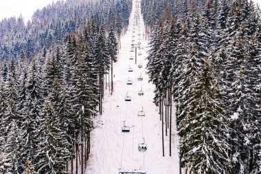 İnsanlar yoğun kar yağışından sonra dağlarda kayak yapmak için teleferik kullanıyorlar.