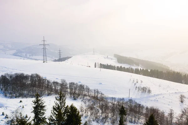 Starker Schneefall in den Bergen am sonnigen Tag, luftige Landschaft. Stromversorgung in hügeliger Gegend — Stockfoto