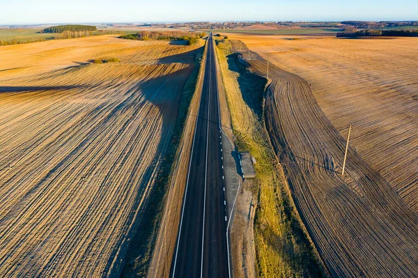 An empty beautiful road goes straight to the horizon. Treated fields in Belarus. Aerial photo