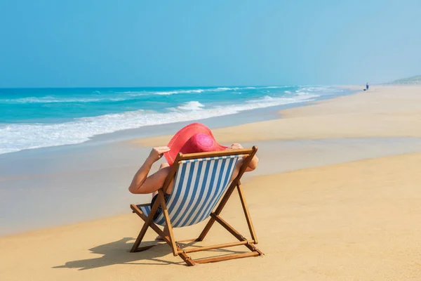 Gelukkige vrouw in rode sunhat op het strand — Stockfoto