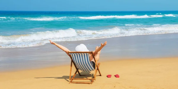 Šťastná žena v bílém klobouku proti slunci seběhla na pláži — Stock fotografie