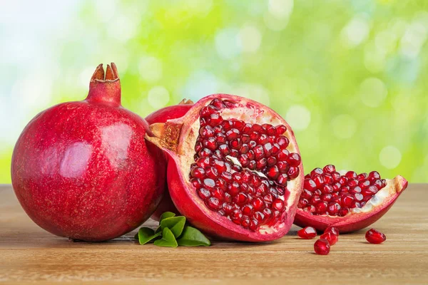Pomegranates whole and cut on wooden table — Stock Photo, Image