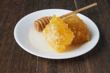 Petek ve bal beyaz bir plaka üzerinde sopa 