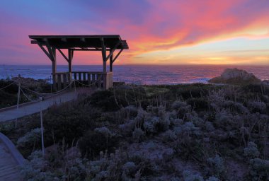 Dramatic clouds at sunset behind a public walkway and gazebo at Asilomar State Beach in Pacific Grove on the Monterey Peninsula of California clipart