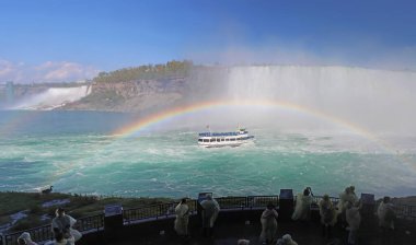 Niagara Şelalesi, Kanada - 29 Mayıs 2017: Turistler Niagara Şelalesi 'nin Kanada tarafında yer alan tam bir gökkuşağı altında Nal Şelalesi' nin öfkeli kataraktlarına yaklaşan Sislerin Kızı 'nı izliyorlar..
