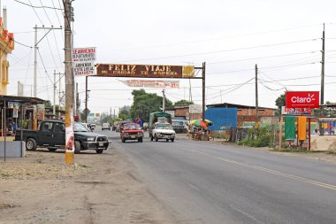 NARANJAL, ECUADOR - 21 Temmuz 2011: Arabalar ve kamyonlar, Ekvador 'un Guayas Eyaleti' nin güney kesimindeki Naranjal şehrinin ana caddelerinden biri boyunca insan ve yol kenarındaki satıcıların yanından geçiyor.