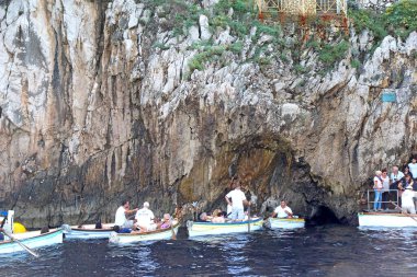 CAPRI, İtalya - 10 Ekim 2014: Capri Adası 'ndaki ünlü Blue Grotto' ya girmek için bekleyen küçük tekneler içindeki turistler. Operatörler, Roma zamanında inşa edilmiş küçük bir delikten tekneleri geçiriyorlar..