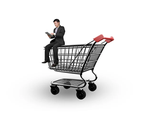 Man using digital tablet and sitting on shopping cart — Stock Photo, Image