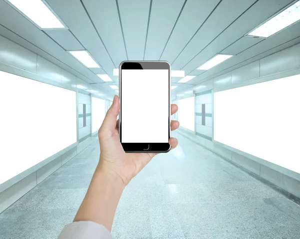 Mujer mano sosteniendo el teléfono inteligente en el paso subterráneo —  Fotos de Stock