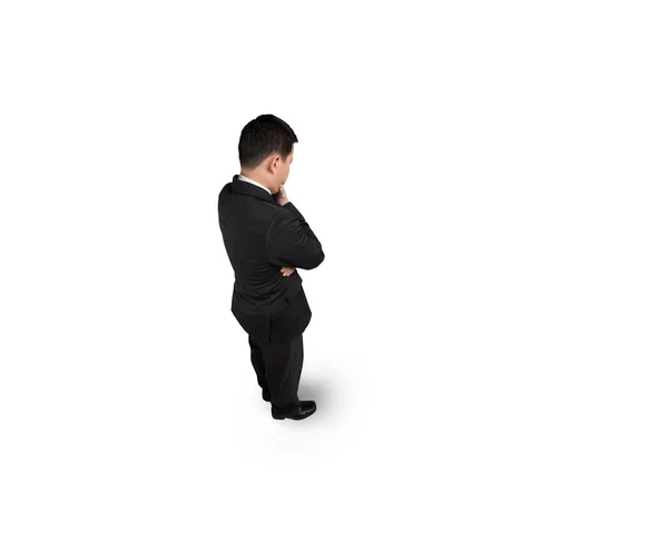 Standing businessman holding hand on chin and thinking — Stock Photo, Image