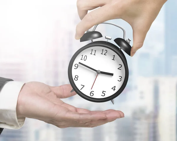 Woman hand giving one alarm clock to man hand — Stock Photo, Image
