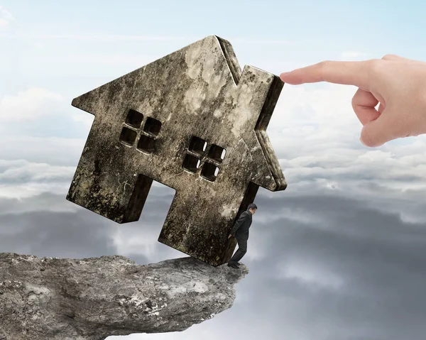 Man holding old house on cliff edge with hand pushing — Stock Photo, Image