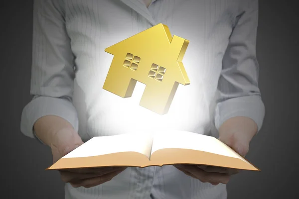 Hands holding open book with golden house — Stock Photo, Image