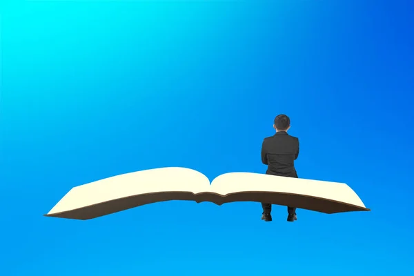 Man sit on book flying in the blue sky — Stock Photo, Image