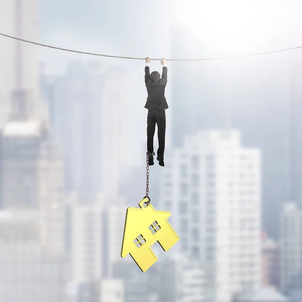 Businessman shackled by gold house hanging on rope — Stock Photo, Image