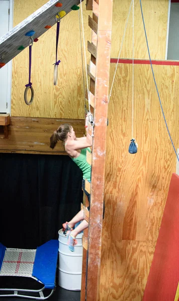 Joven atleta ninja, Sara Heesen, tirando hacia arriba como ella asciende la escalera de salmón durante una competición ninja . — Foto de Stock