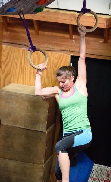 Młodych kobiet sportowiec pręży mięśnie ramion, jak ona huśtawki z jednym pierścieniem do innego podczas konkursu wojownika ninja, która odbyła się w Albuquerque, Nowy Meksyk — Zdjęcie stockowe