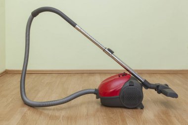 Bos bir odada parke üzerinde kırmızı bir elektrikli süpürge görüntüsünü.