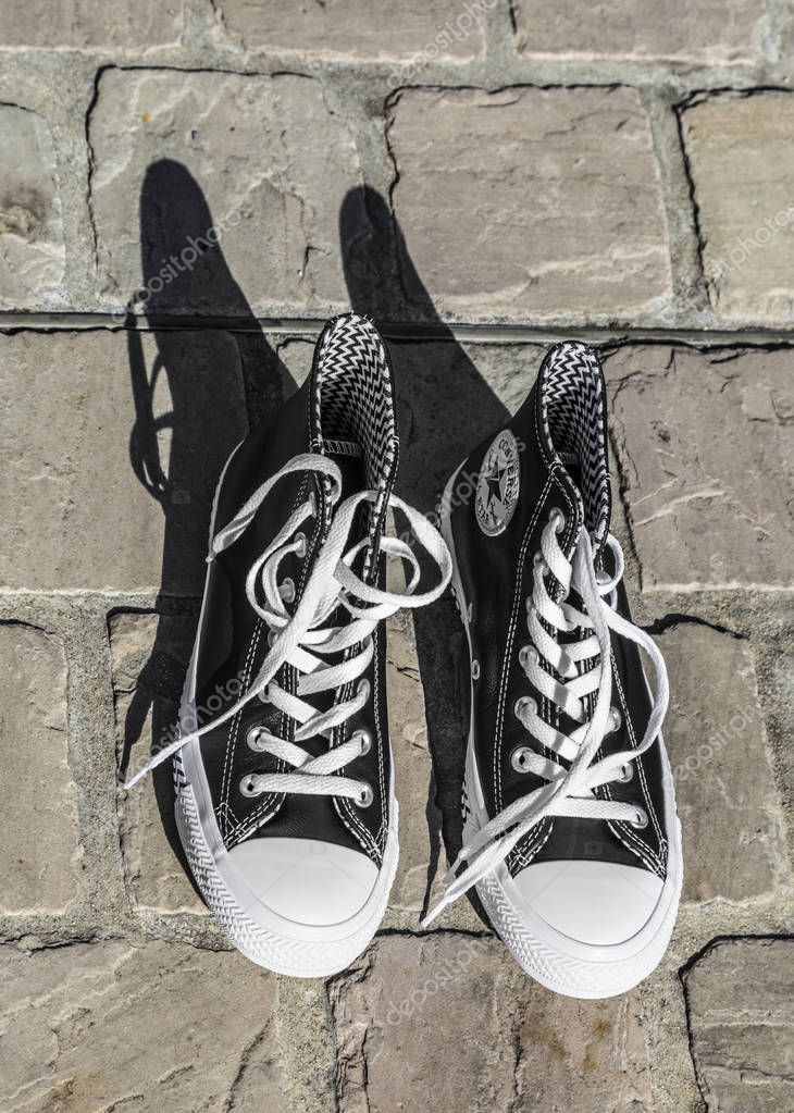 Chartres, France - Spetember 2, 2019: Aerial view image of a pair of All Star Converse sneakers on a cobblestone street.