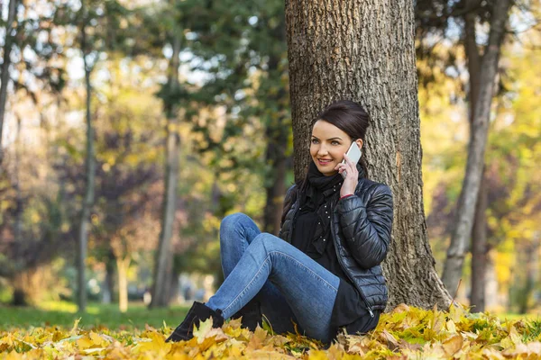 Donna su un cellulare in una foresta in autunno — Foto Stock