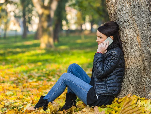 Kobieta na komórce w lesie jesienią — Zdjęcie stockowe