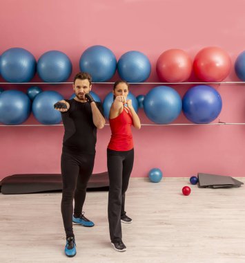 Spor salonunda egzersiz yapan genç bir çiftin resmi.