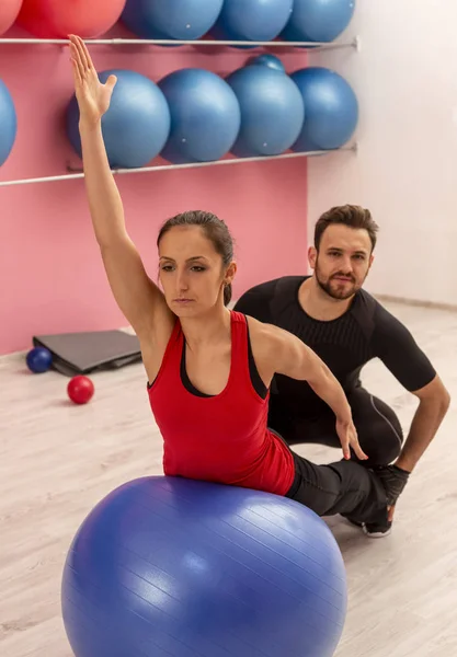 Junge Frau Macht Mit Hilfe Ihres Trainers Übungen Mit Fitnessball — Stockfoto