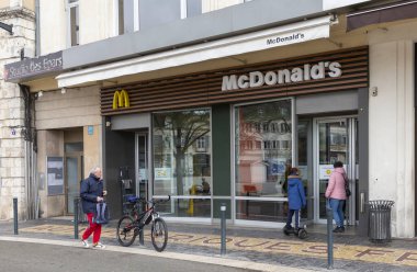 Chartres, Fransa - 15 Mart 2020: Coronavirus salgınının artması nedeniyle Fransız hükümeti kısmi tecrit emri verdikten sonra bir kadın McDonald 's restoranının kapısını kontrol ediyor.