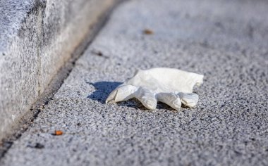 2020 'deki Coronavirus krizi sırasında bir ameliyat eldiveninin yakın plan görüntüsü düştü ve sokağa atıldı..