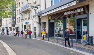 Chartres, Fransa - Nisan 04, 2020: 2020 Coronavirus krizinin bir aydan fazla süren tam tecrit döneminde, Paskalya 'dan bir gün önce, açık sokak pazarına erişmek için toplumsal uzaklık kurallarına uygun sırada bekleyen insanlar