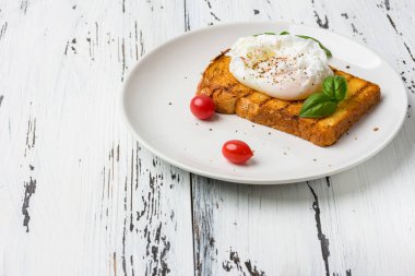 Ahşap masada bir parça ekmek üzerinde haşlanmış yumurta.