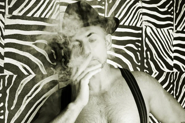 Macho in een vilten hoed en een sigaar in de handen van een foto gemaakt in zwart-wit — Stockfoto